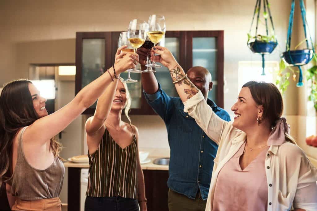 A small group of people raising their champagne glasses during a house-warming party