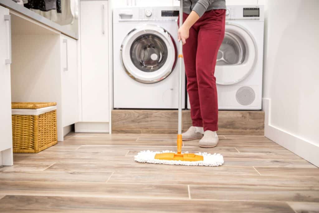 A woman cleaning the floor of the laundry room