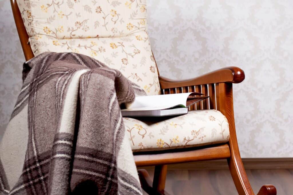 A rocking chair with a blanket and a book