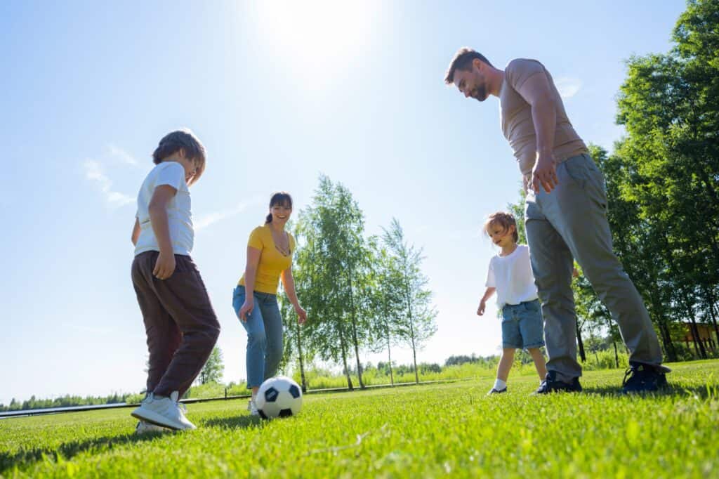 A family is playing football in the concept of 'best parks and green spaces in Harrow'.