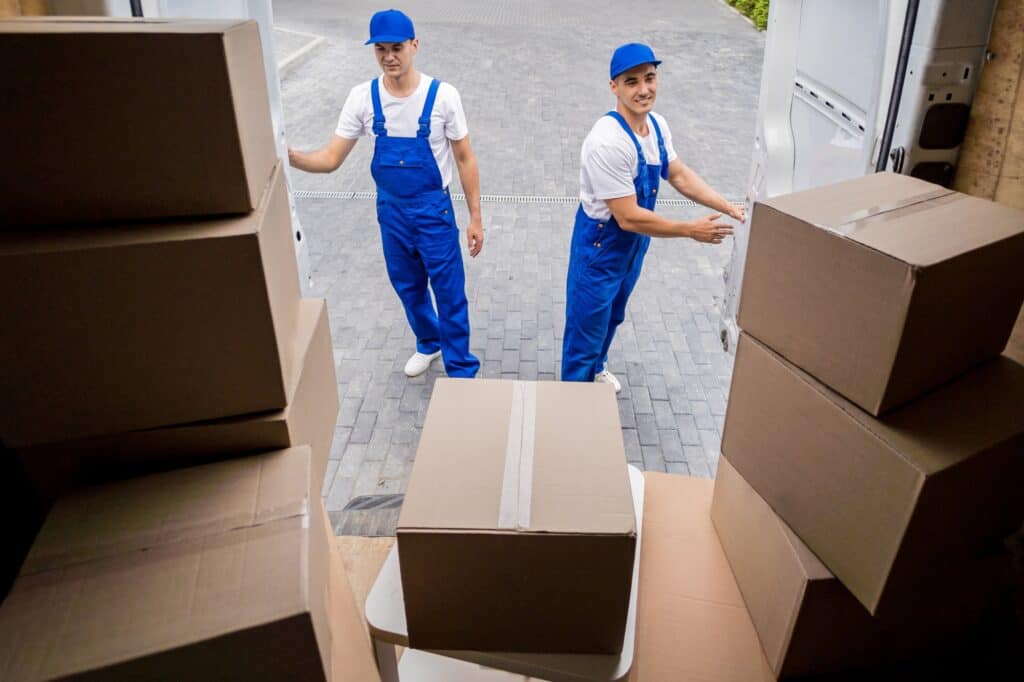 Professional movers at the back of the moving van filled with boxes in the concept of 'How to Choose the Best Home Removals Company'.