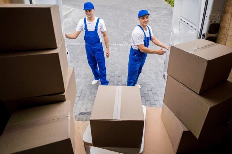 Professional movers at the back of the moving van filled with boxes in the concept of 'How to Choose the Best Home Removals Company'.
