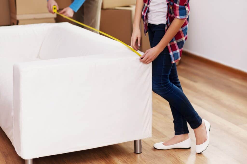 Cropped image of a young couple measuring a sofa for the move